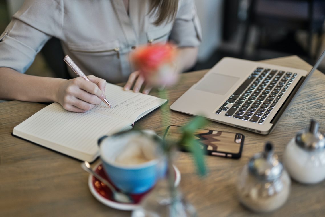 RadioMarocCulture Person Writing On A Notebook Beside Macbook 1766604